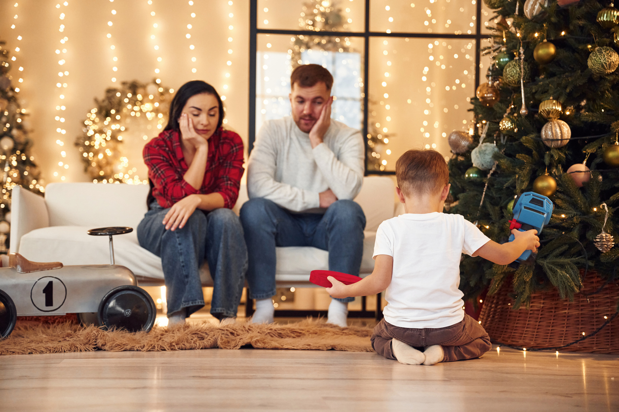 family stressed out sitting next to Christmas tree.