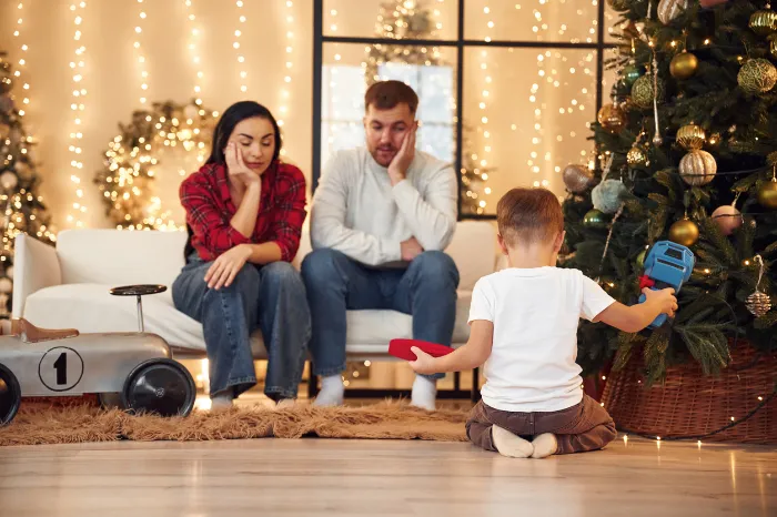 family stressed out sitting next to Christmas tree.