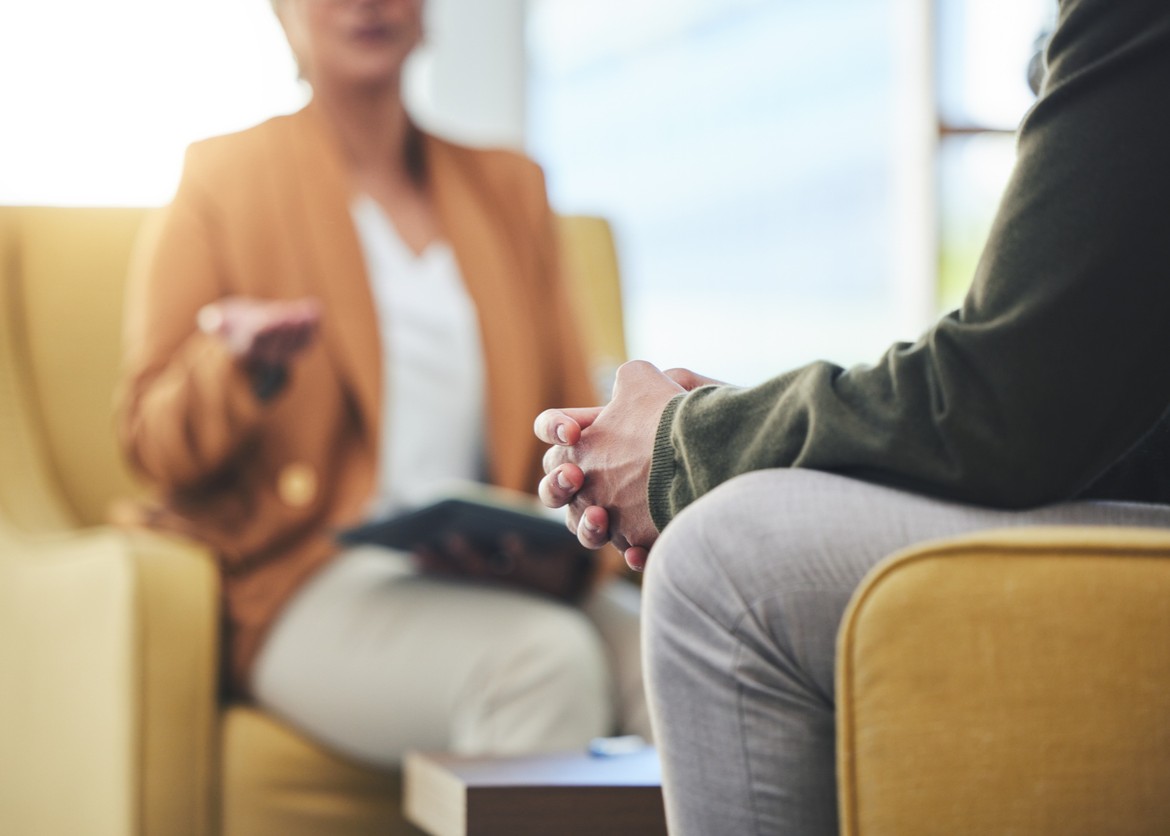 Man, hands and listening for therapy, sofa or advice from woman for mental health, psychology or care. Psychiatrist, patient and frustrated in clinic, session or couch for help, anxiety or depression