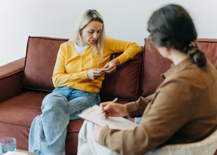 A woman patient, sitting on the couch during a consultation with a psychologist, talks about her difficulties in life, stress and relationship problems.
