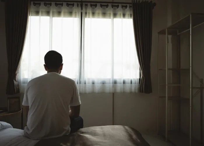 Silhouette depressed man sadly sitting on the bed in the bedroom. Sad asian men suffering depression insomnia awake and sit alone on the bed in bedroom. Depression health people concept.