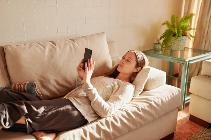 woman laying down using a mental health app on her phone.